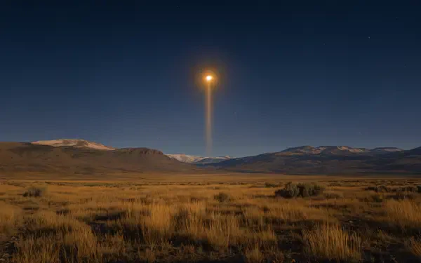 A stunning landscape featuring mountains under a dark sky, illuminated by a solar eclipse casting a beam of sunlight, perfect for a 4K Ultra HD desktop background.
