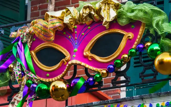 A vibrant Mardi Gras mask adorned with colorful decorations, set against a brick backdrop, brightens this HD desktop wallpaper, capturing the festive spirit of the celebration.