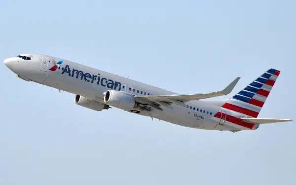 An American Airlines airplane takes off against a clear blue sky, showcasing its distinctive livery. This HD image serves as a striking desktop wallpaper.