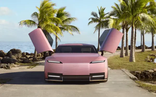 A pink Jaguar Type 00 sports car with butterfly doors open, parked on a palm-lined coastal road, captured in 8K Ultra HD as a PC desktop wallpaper.