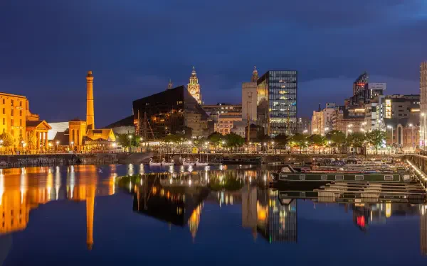 HD PC desktop wallpaper featuring a vibrant night cityscape of Liverpool, with illuminated buildings reflecting on the calm waterfront under a deep blue sky.
