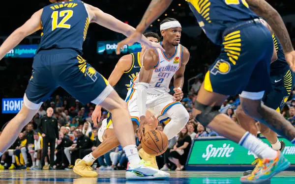 Action-packed NBA Finals moment featuring Shai Gilgeous-Alexander dribbling past defenders, captured in HD for a dynamic basketball sports wallpaper.