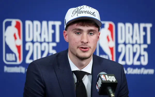 Cooper Flagg in a suit and Mavericks cap at the 2025 NBA Draft, featured in a high-definition PC desktop wallpaper and background.