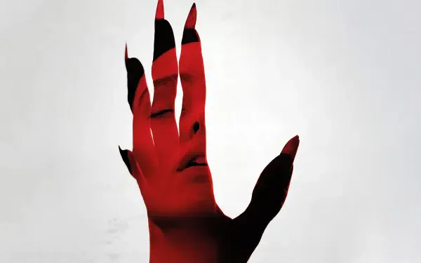 Nosferatu (2024) 4K Ultra HD desktop wallpaper featuring a red-tinted hand with black nails partially obscuring a pale face in the background.