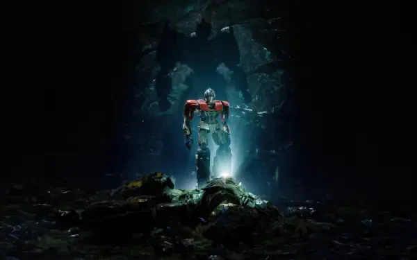 A 4K Ultra HD PC desktop wallpaper featuring Optimus Prime from Transformers One standing illuminated in a dark, cavernous environment.