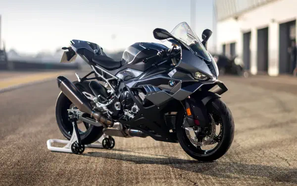 Black BMW S1000RR sports bike on a racetrack pit lane, shot in crisp 4K Ultra HD as a PC desktop wallpaper/background.