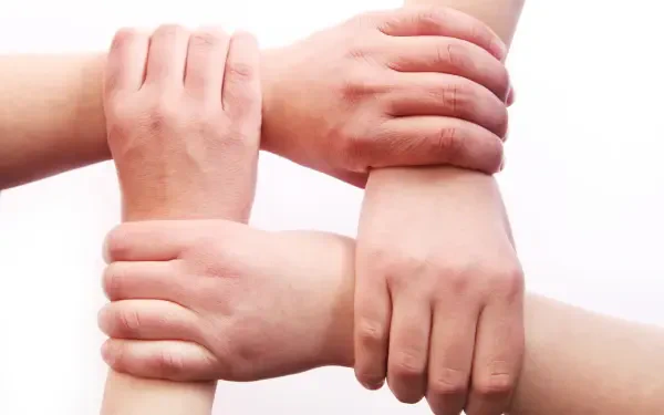 HD PC desktop wallpaper/background of four hands grasping wrists in a square, showing people united—family and team together.