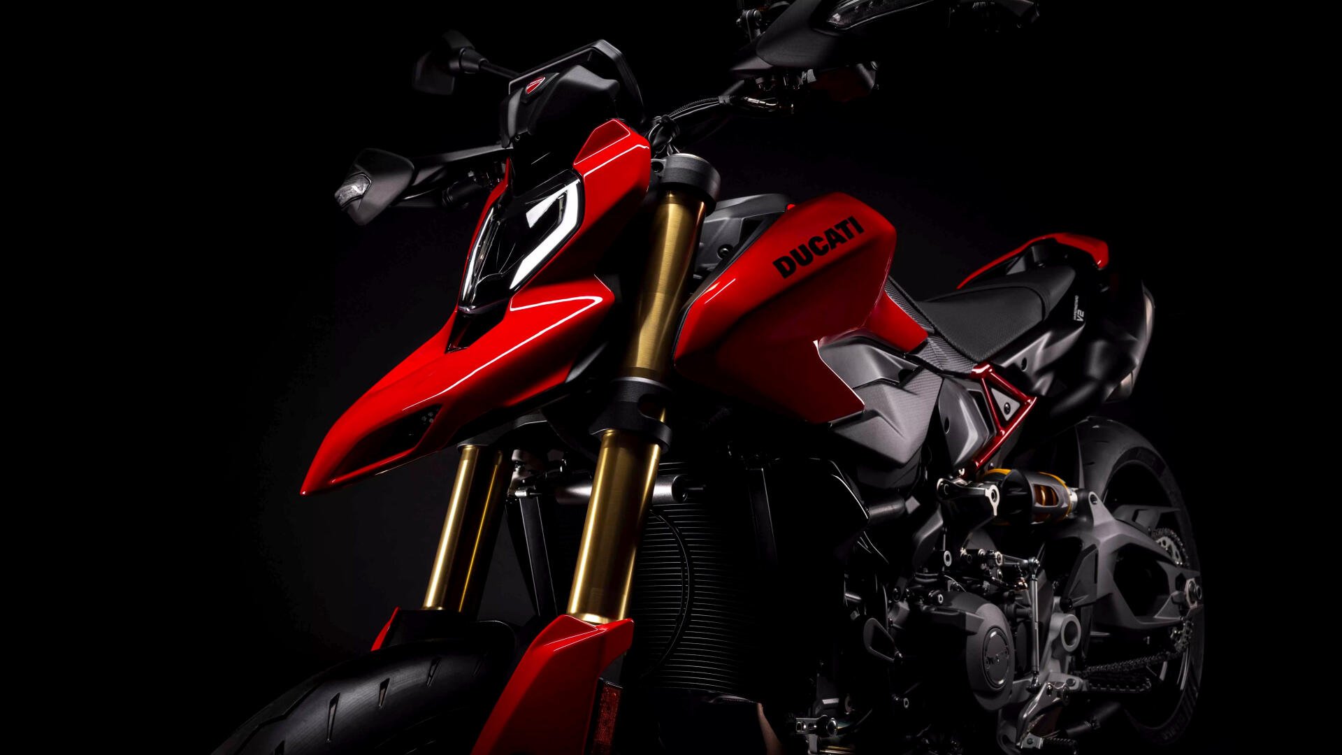 Red Ducati Hypermotard V2 motorcycle in dramatic low-light on black background — 8K Ultra HD PC desktop wallpaper and background.