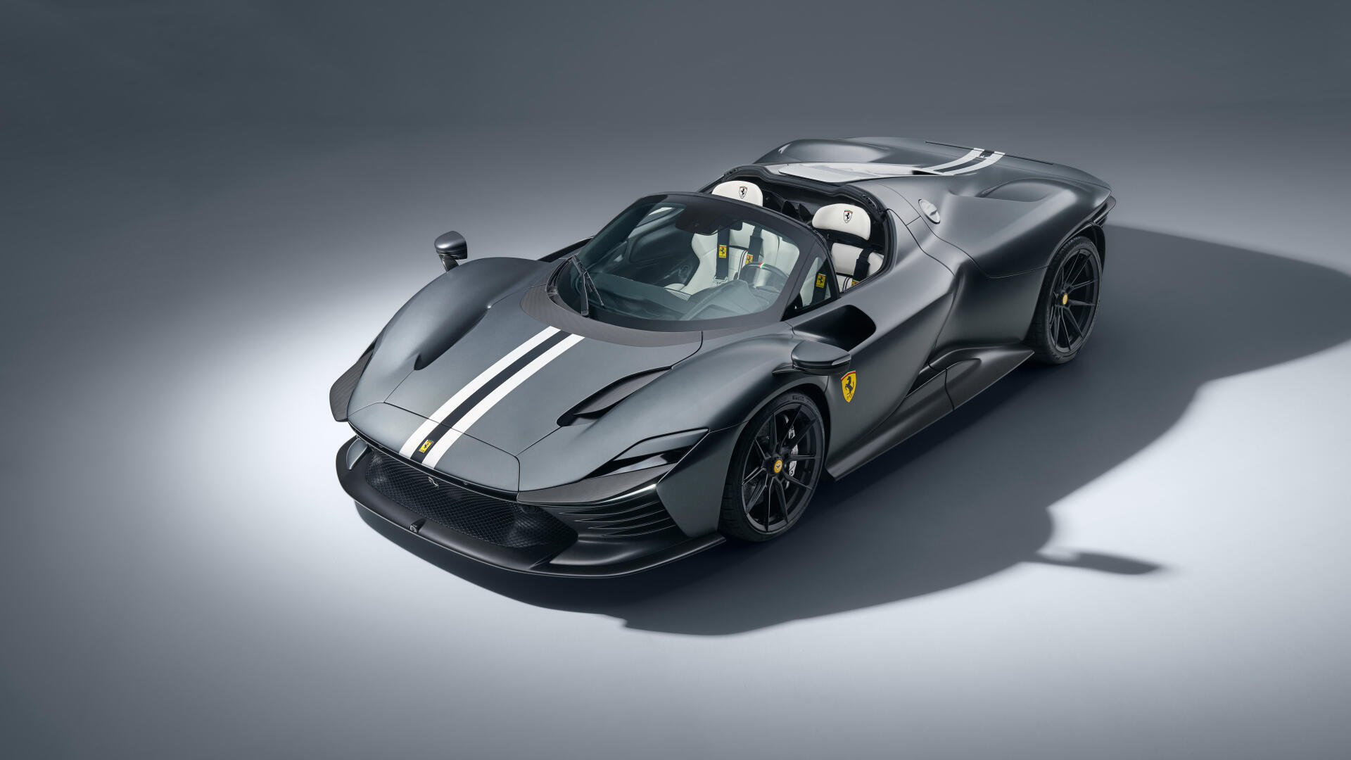 Black Ferrari Daytona SP3 with white racing stripe, three-quarter studio view on gray backdrop — 8K Ultra HD PC desktop wallpaper/background.