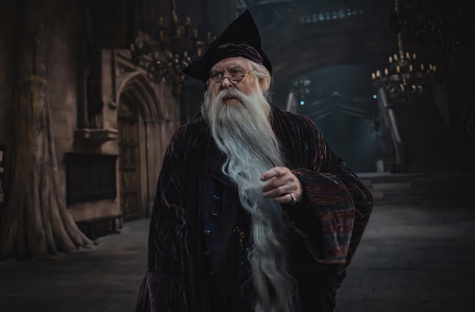 HD PC desktop wallpaper: Albus Dumbledore from the TV show Harry Potter (2027) in robes with a long white beard, standing in a dim, candlelit Great Hall.