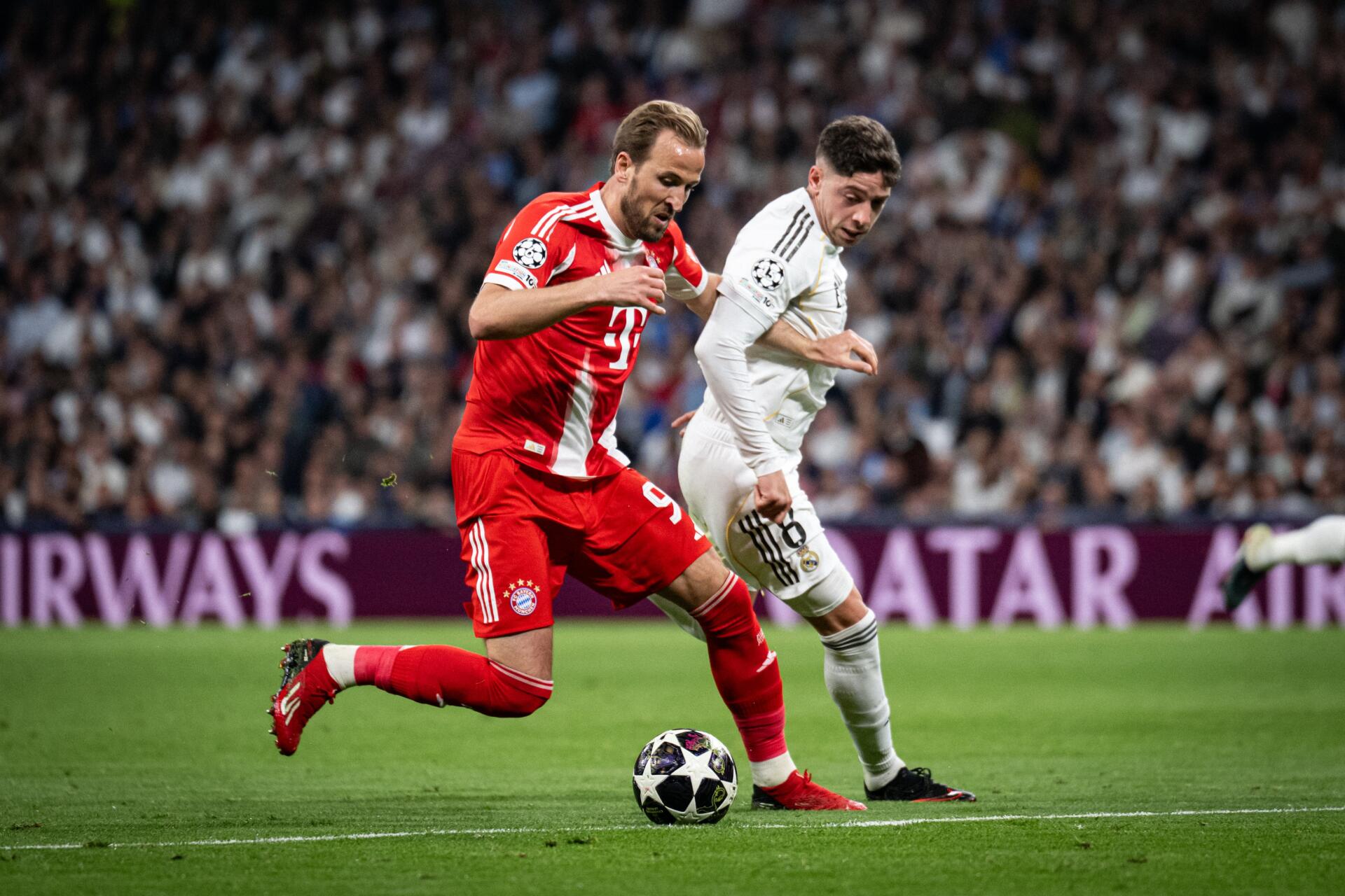 4K Ultra HD PC desktop wallpaper: intense soccer duel with FC Bayern Munich in red and Real Madrid C.F. in white racing across a packed stadium pitch.