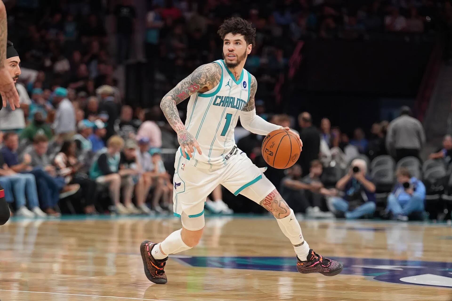 NBA action: Charlotte Hornets guard in teal-and-white uniform dribbling past a defender on the court — dynamic 2K Quad HD PC desktop wallpaper.
