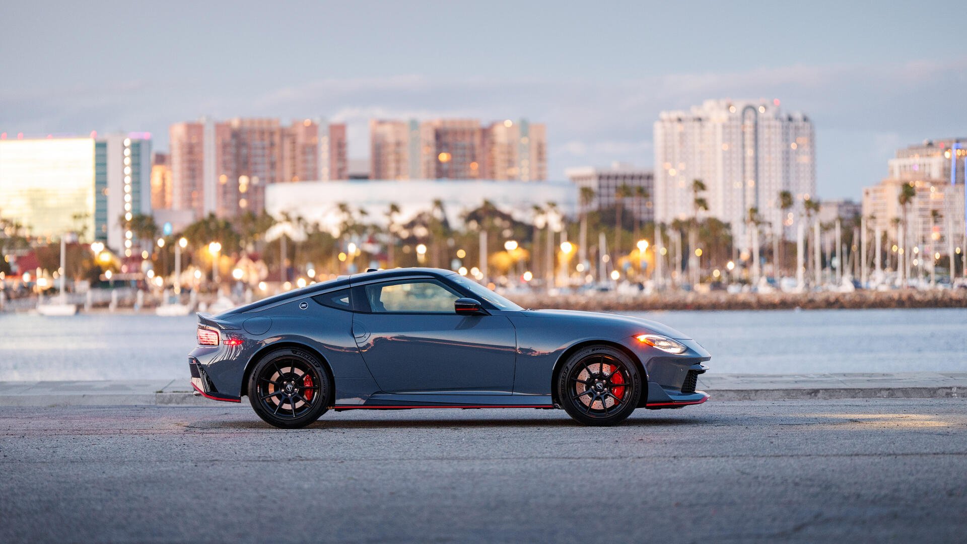 Blue Nissan Z Nismo sports car side profile by a waterfront city — 4K Ultra HD PC desktop wallpaper background.