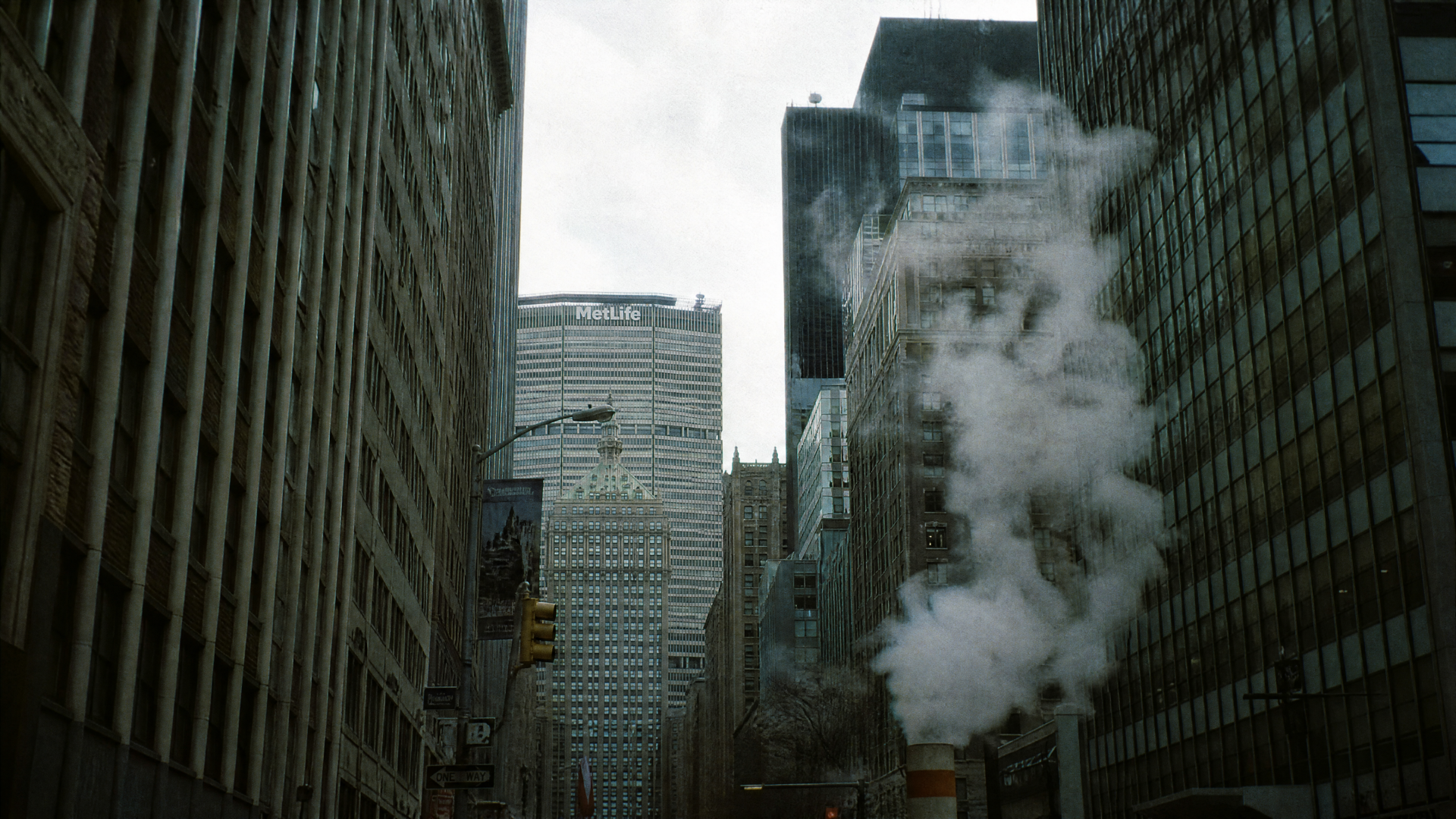 Concrete jungle of towering skyscrapers framing a misty avenue with steam rising from a street vent — 4K Ultra HD PC Desktop Wallpaper and Background.