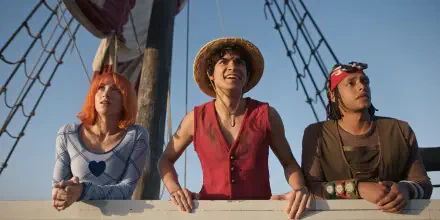 One Piece (Live Action) TV show trio on a ship deck, straw-hatted leader smiling between two crewmates — 2K Quad HD PC desktop wallpaper.