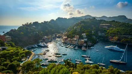 5K Ultra HD PC desktop wallpaper: sunlit Ligurian port on the Italian Mediterranean, yachts and fishing boats in a turquoise sheltered bay framed by green hills.