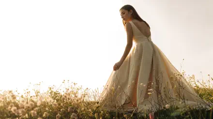 4K Ultra HD PC Desktop Wallpaper and Background — backlit woman in a flowing gown walks through a sunlit wildflower meadow at golden hour.