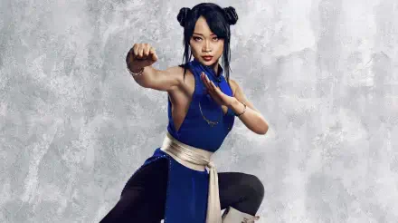 Street Fighter (2026) 2K Quad HD PC wallpaper: female fighter in a blue outfit with white sash, poised in a martial-arts stance against a textured gray background.
