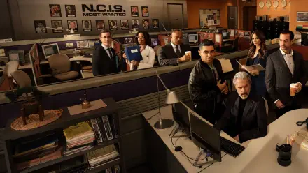 NCIS team in a busy office bullpen with desks, monitors and an evidence board — 2K Quad HD PC desktop wallpaper/background.