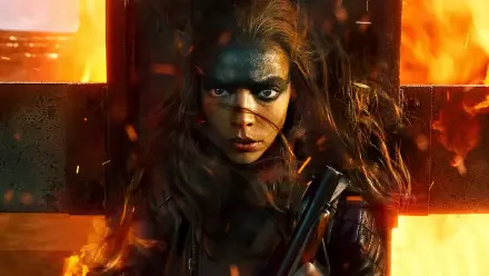 Furiosa: A Mad Max Saga — close-up of Furiosa with black warpaint, windblown hair, a rifle and roaring orange flames behind a metal cross; 4K Ultra HD PC desktop wallpaper background