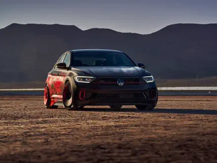 HD PC desktop wallpaper: vehicle — a black Volkswagen Jetta parked on a desert flat at dusk, low-angle view highlighting its sporty front end with mountains in the background.