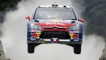 Citroën C4 WRC rally vehicle airborne in Red Bull/Total livery with smoke trail — 4K Ultra HD PC desktop wallpaper/background.