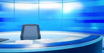 Tomodachi Life: Living the Dream HD PC desktop wallpaper showing a sleek blue broadcast desk with an empty chair and scattered papers in a bright, futuristic studio.