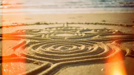 Close-up of intricate circular sand art etched in wet beach sand at sunrise, warm light leaks — 4K Ultra HD PC desktop wallpaper and background.