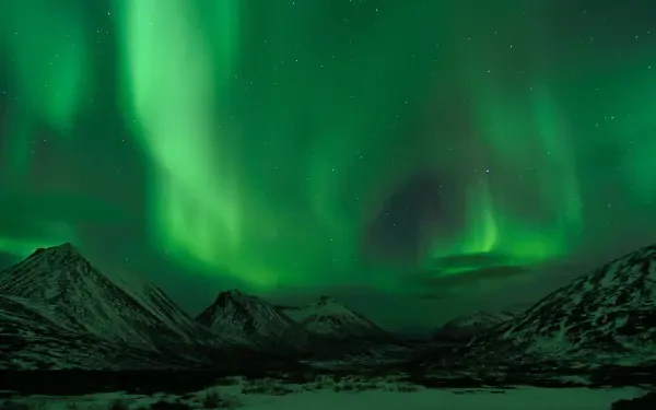 HD PC desktop wallpaper and background: planetary landscape view of snow-capped mountains under a vivid green aurora borealis sweeping across a starry space sky.