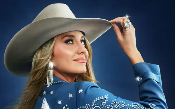 Smiling country singer in a rhinestone blue jacket and cowboy hat, tipping her brim at the CMA Awards — HD PC desktop wallpaper and background.