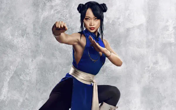 Street Fighter (2026) 2K Quad HD PC wallpaper: female fighter in a blue outfit with white sash, poised in a martial-arts stance against a textured gray background.