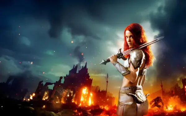 Red Sonja (2023) 4K Ultra HD PC desktop wallpaper — red-haired armored warrior brandishes a sword before a burning, stormy ruined cityscape.