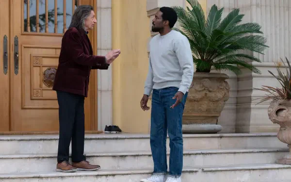 5K Ultra HD TV wallpaper for Wonder Man (2026): two characters talk on marble steps outside an ornate doorway flanked by potted palms.