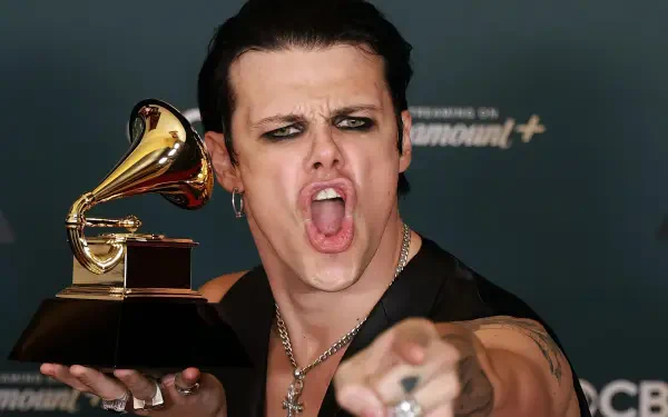 2K Quad HD desktop wallpaper of a punk-rock singer at the Grammy Awards, heavy eye makeup, clutching a Grammy trophy and pointing aggressively toward the camera, music energy and stage presence.