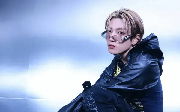 4K Ultra HD PC desktop wallpaper of a K-pop performer in bold, group-inspired stage style: light-haired singer with round glasses and dark layered streetwear against a cool blue backdrop.