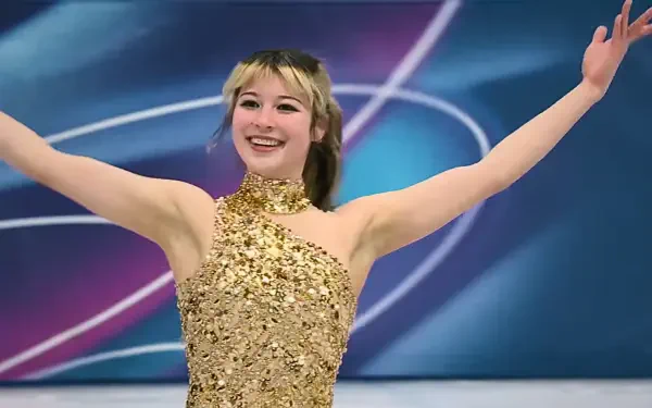 Smiling female figure skater in a gold sequined costume, arms raised on a Winter Olympics–style ice rink, 4K Ultra HD desktop wallpaper.