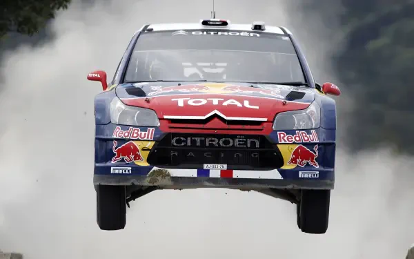 Citroën C4 WRC rally vehicle airborne in Red Bull/Total livery with smoke trail — 4K Ultra HD PC desktop wallpaper/background.