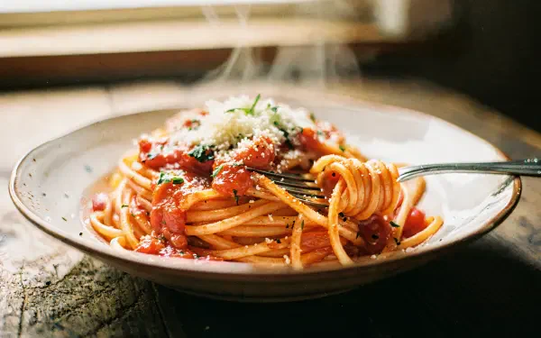 4K Ultra HD PC desktop wallpaper: steaming spaghetti in tomato sauce topped with grated cheese, twirled on a fork over a rustic plate.