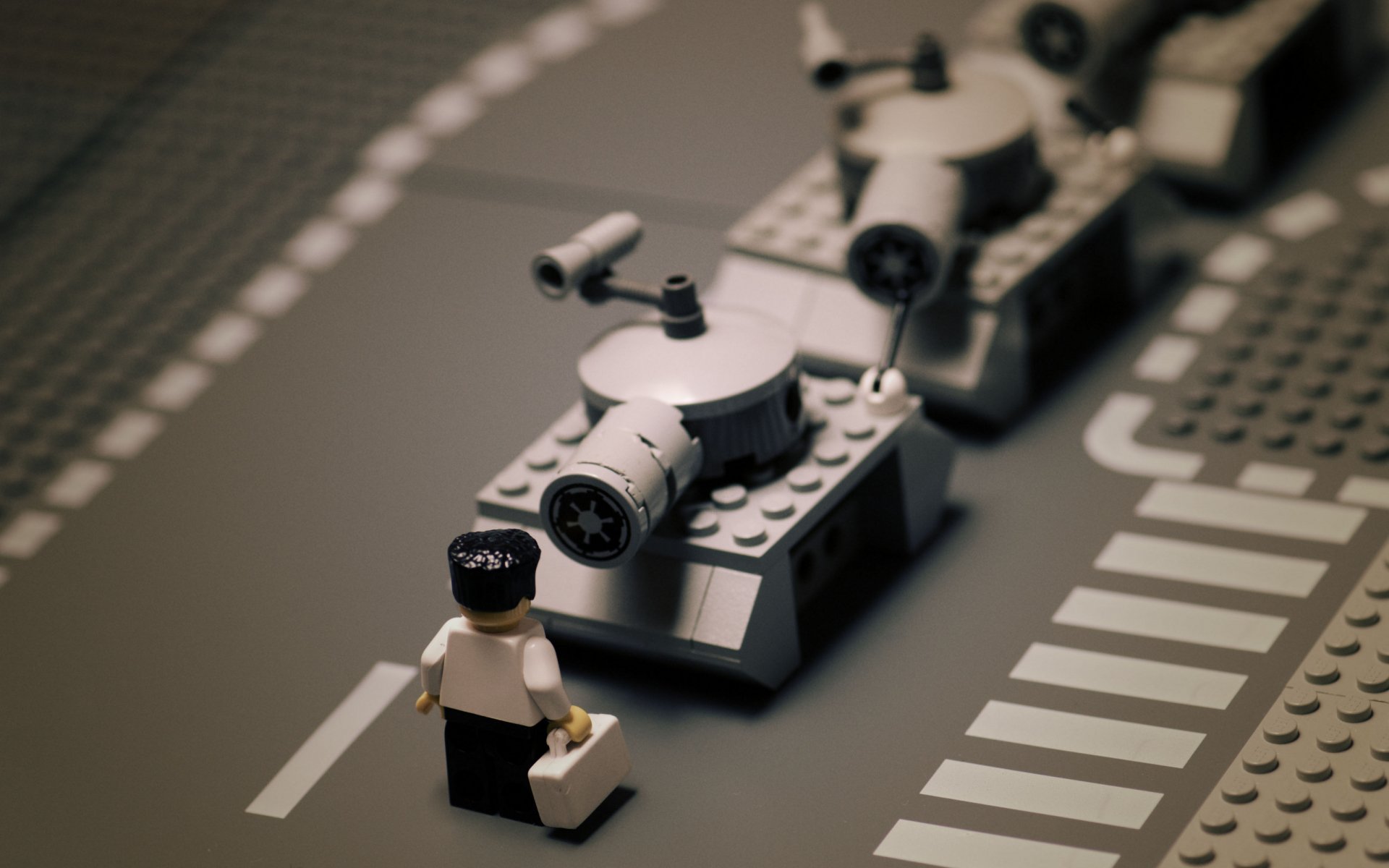 HD desktop wallpaper of a man-made LEGO miniature tank and figurine on a gray road with white lines, capturing detailed and creative LEGO craftsmanship.