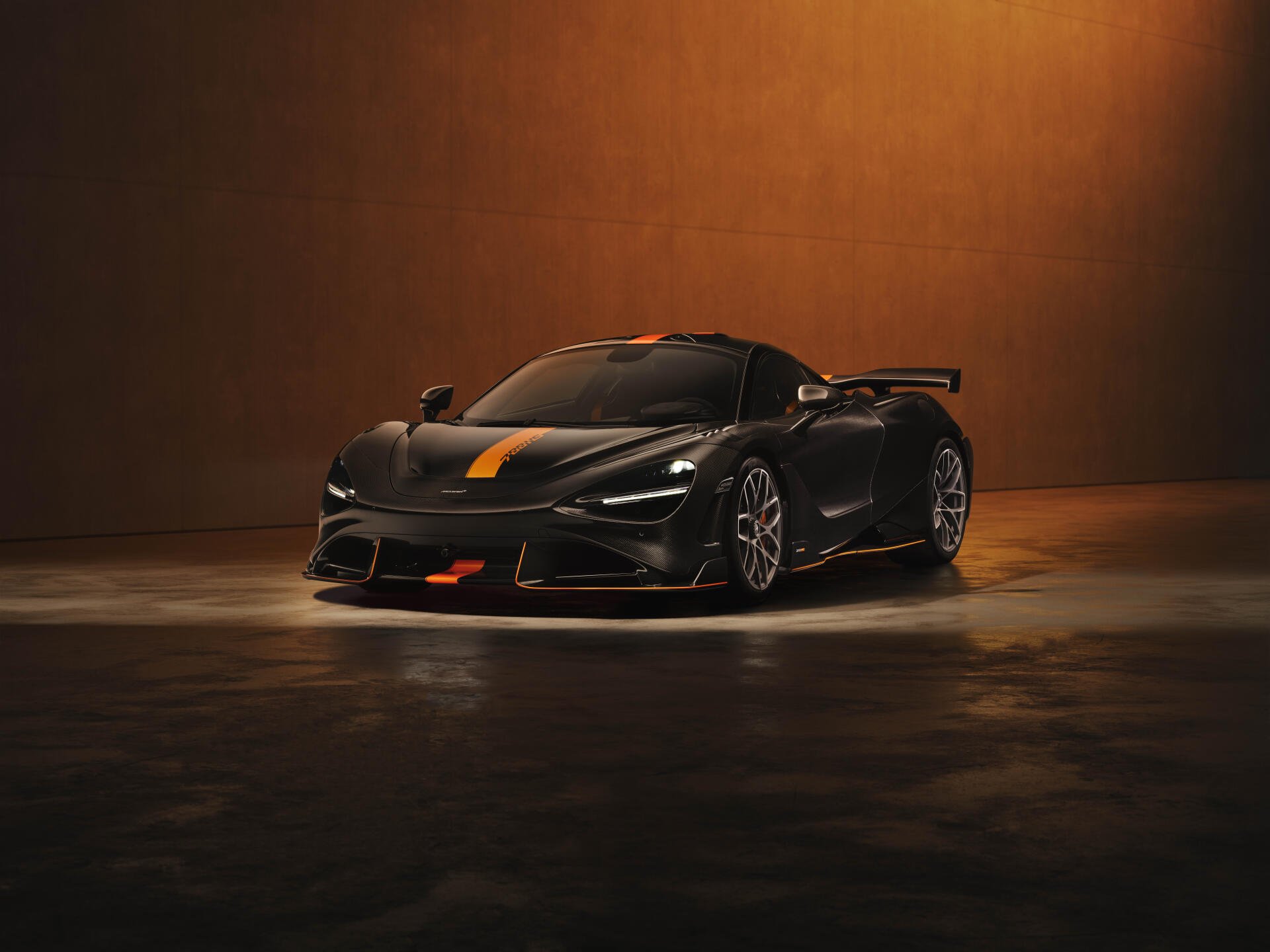 Sleek black McLaren 788HS sports car with orange accents in dim studio lighting, 8K Ultra HD PC desktop wallpaper/background.