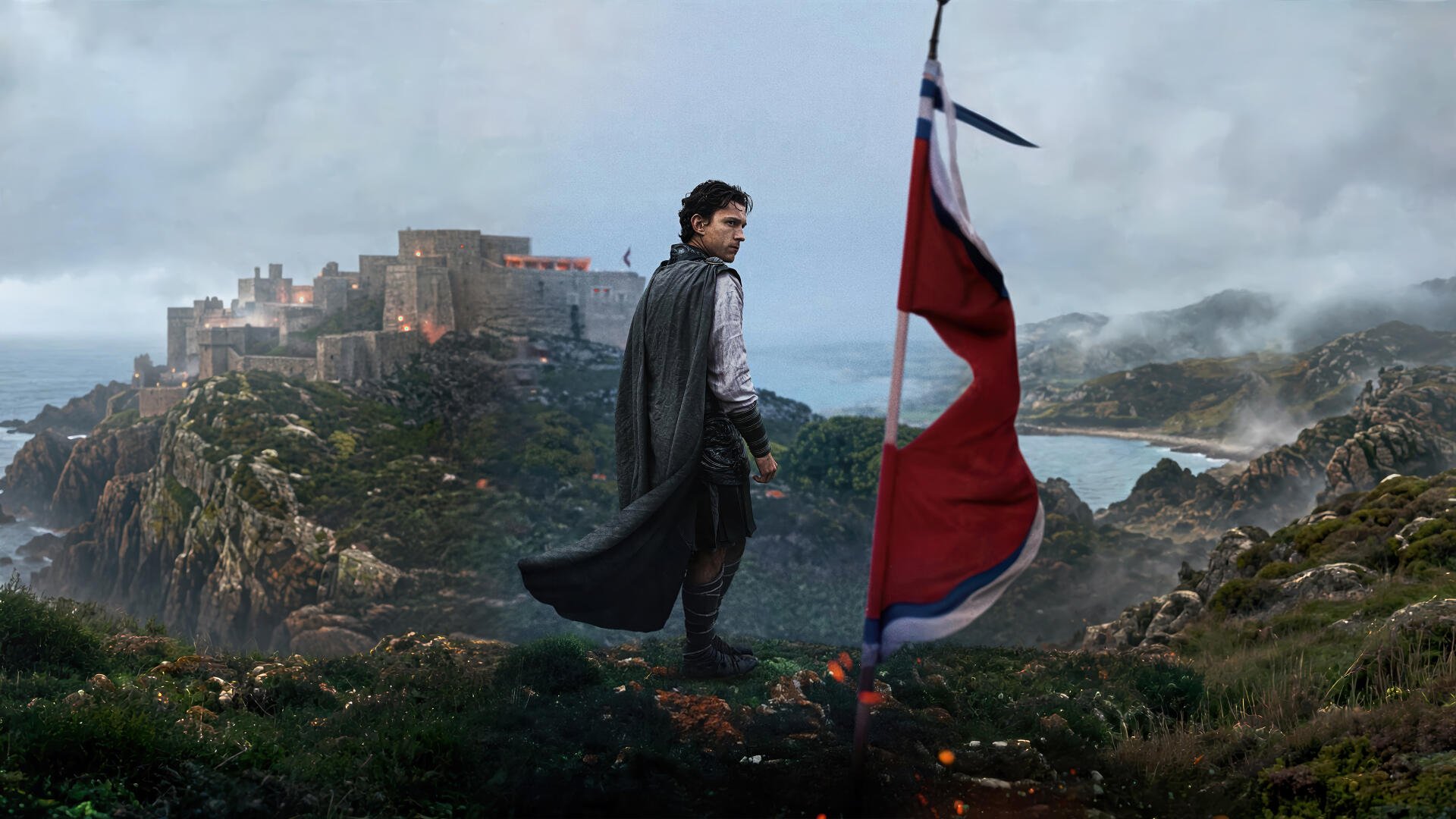 4K Ultra HD PC desktop wallpaper: cloaked hero on a windswept cliff by a tattered red banner, overlooking a coastal fortress and stormy sea — The Odyssey (2026).