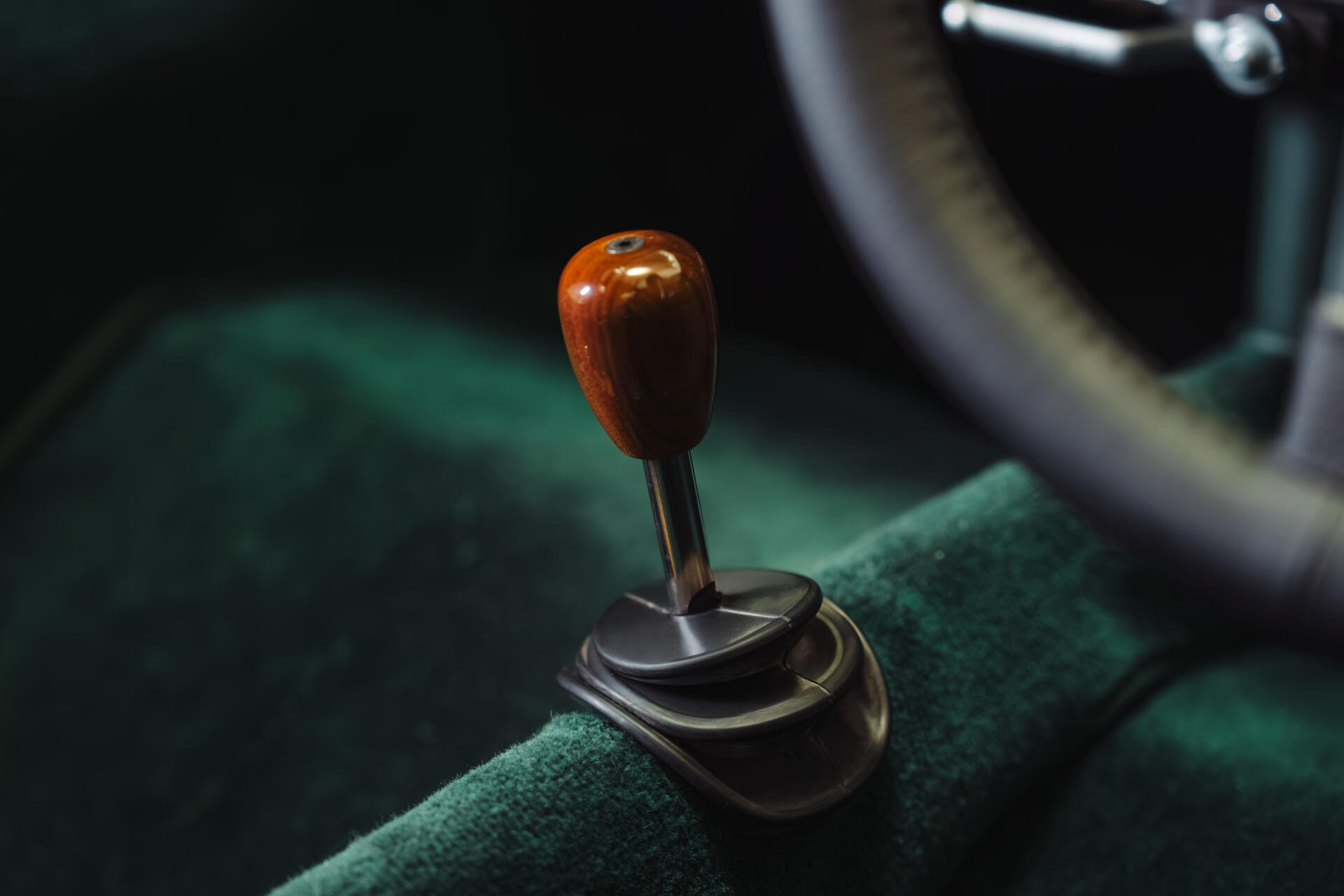 Close-up of a wooden gearshift knob and green interior upholstery in a McLaren G6GT, 8K Ultra HD PC desktop wallpaper.