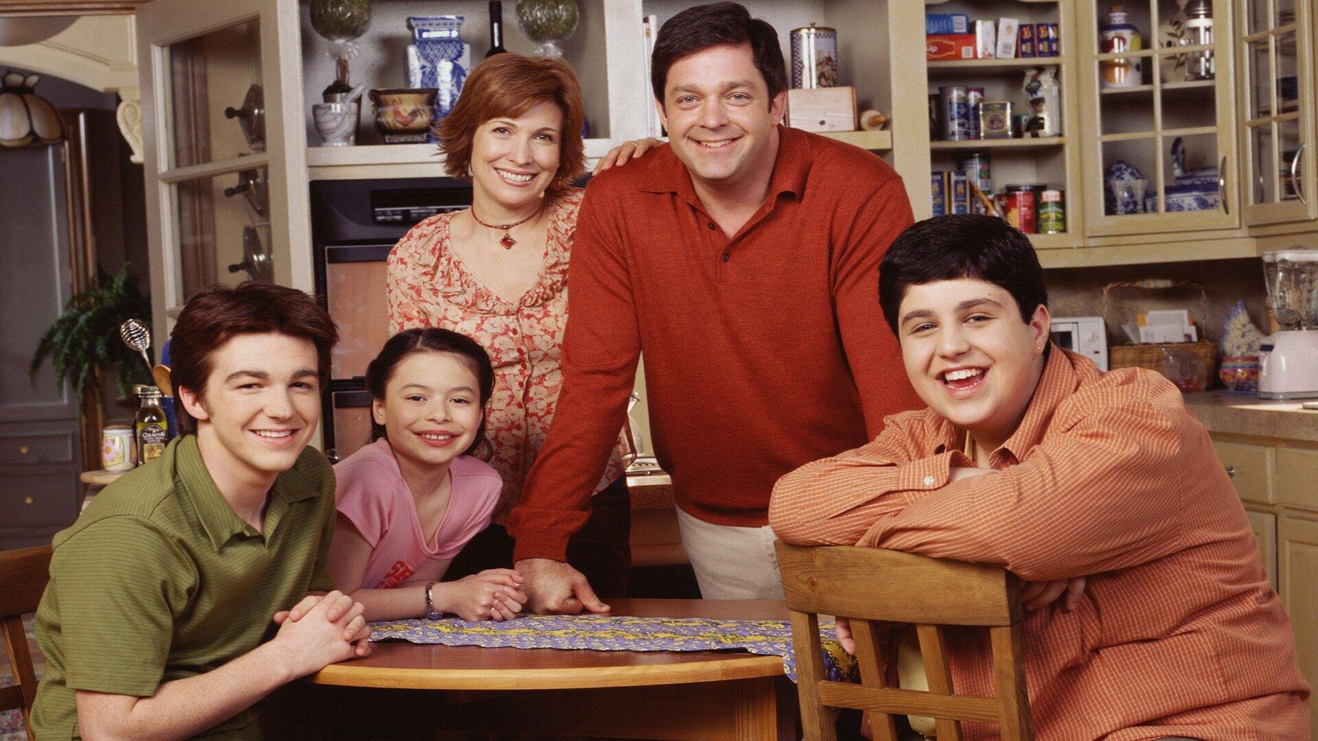 Drake & Josh HD PC desktop wallpaper: cast family portrait in a cozy kitchen, two teen boys and their parents smiling around a table.