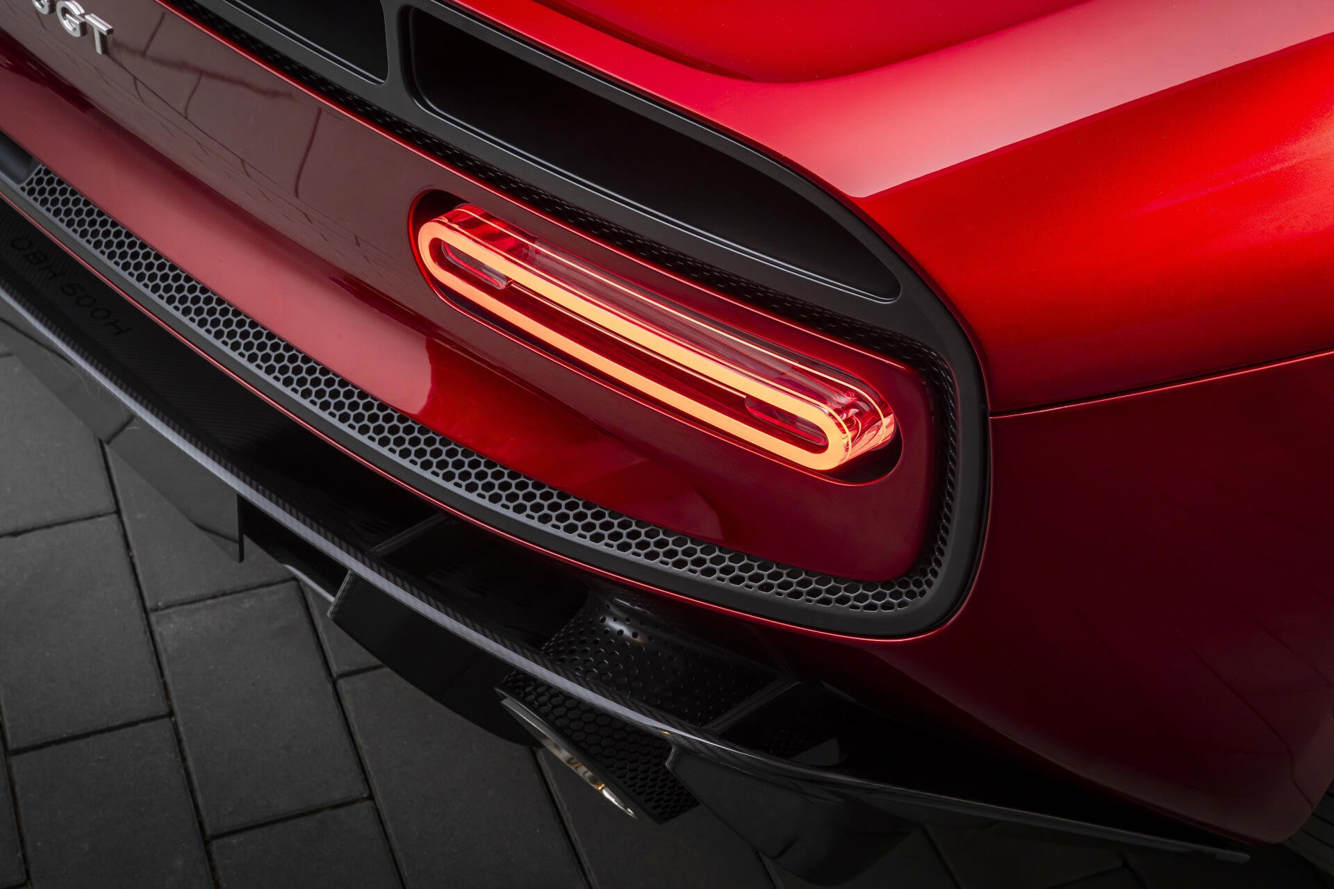 Close-up of the rear taillight and bumper of a red McLaren McL 6GT sports car, 8K Ultra HD PC desktop wallpaper background.