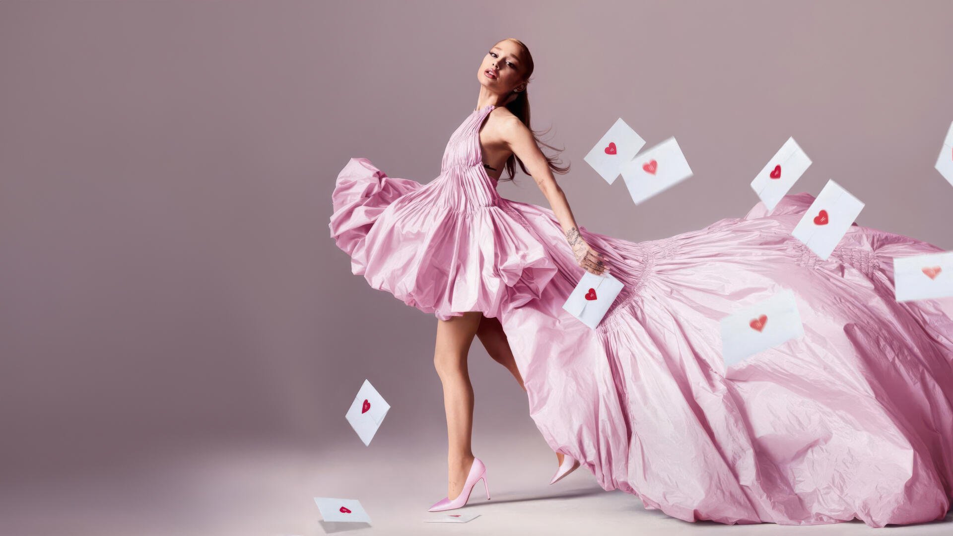 Woman in a flowing pink gown and heels, playing-card hearts drifting around her as she strikes a graceful pose — 4K Ultra HD PC desktop wallpaper.