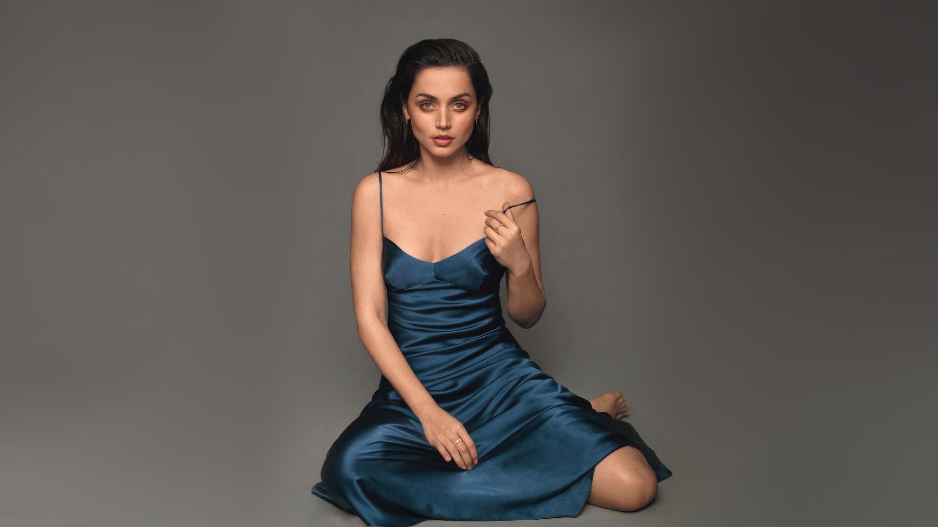 Glamorous celebrity actress portrait seated in a teal satin slip dress, 4K Ultra HD PC desktop wallpaper on a neutral gray background.