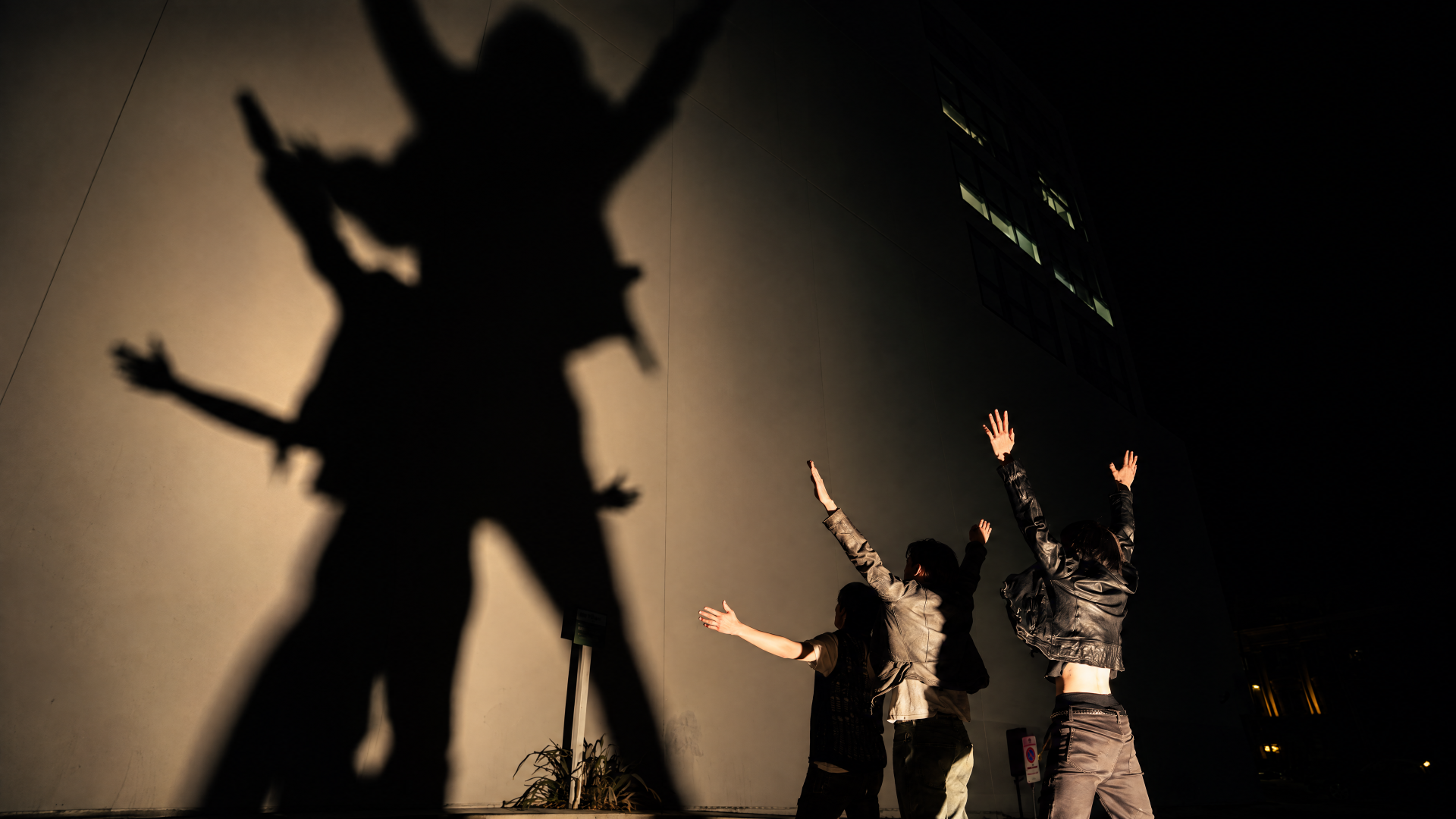 Cortis fashion performers cast dramatic silhouettes and shadows on a backlit wall — 4K Ultra HD PC desktop wallpaper/background.