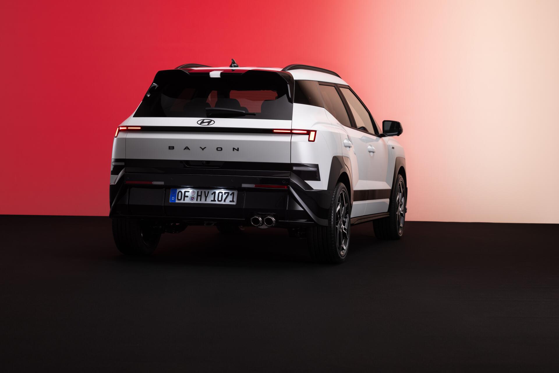 8K Ultra HD desktop wallpaper of a white Hyundai Bayon SUV viewed from the rear against a red and white studio backdrop.