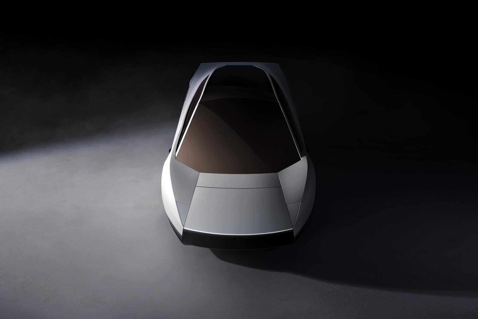 Front view of a silver Tesla Roadster concept car in a dark studio, 2K Quad HD PC desktop wallpaper and background.