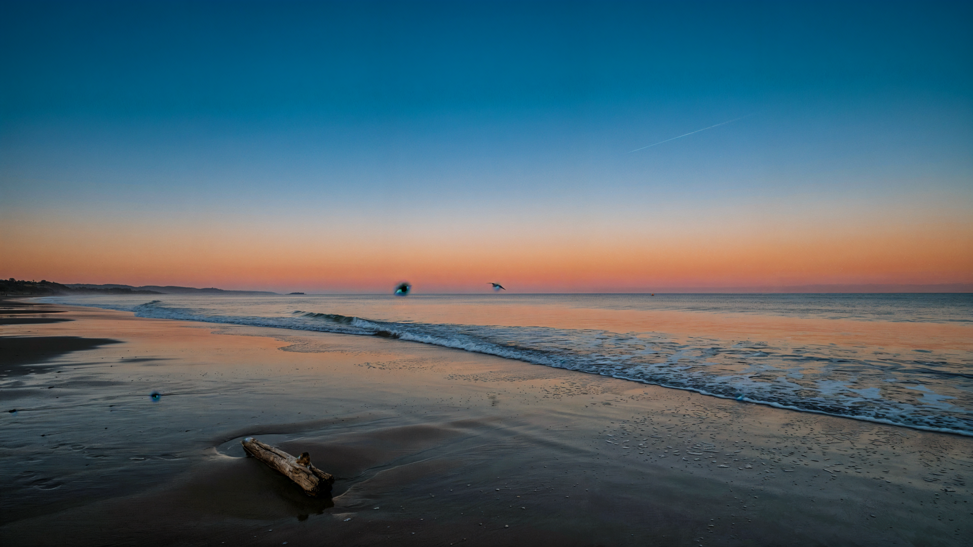 4K Ultra HD PC desktop wallpaper of a quiet ocean shore at sunset, with gentle waves washing across the beach.